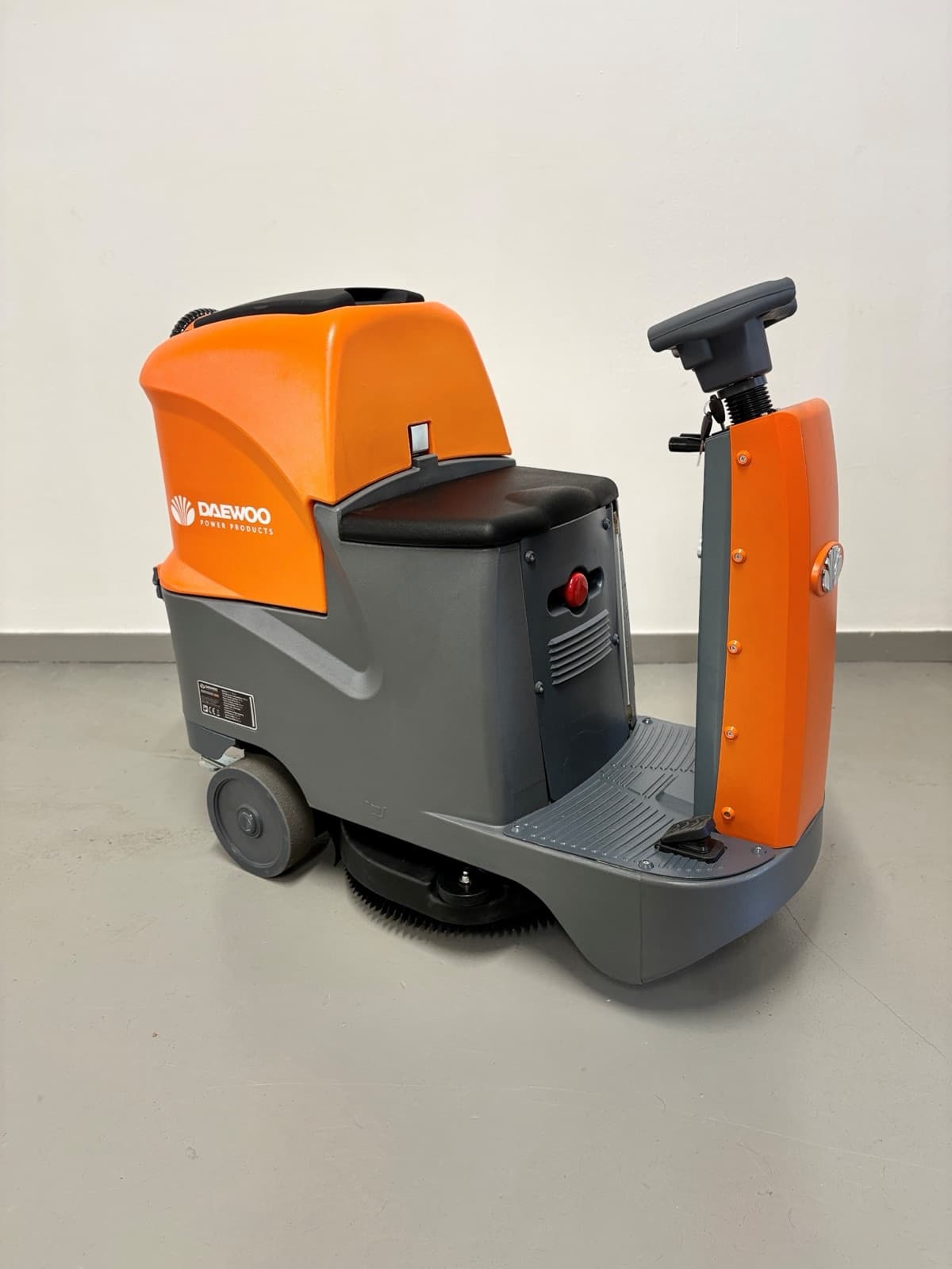 Orange-graue Aufsitz-Scheuersaugmaschine mit Lenkrad und Trittfläche